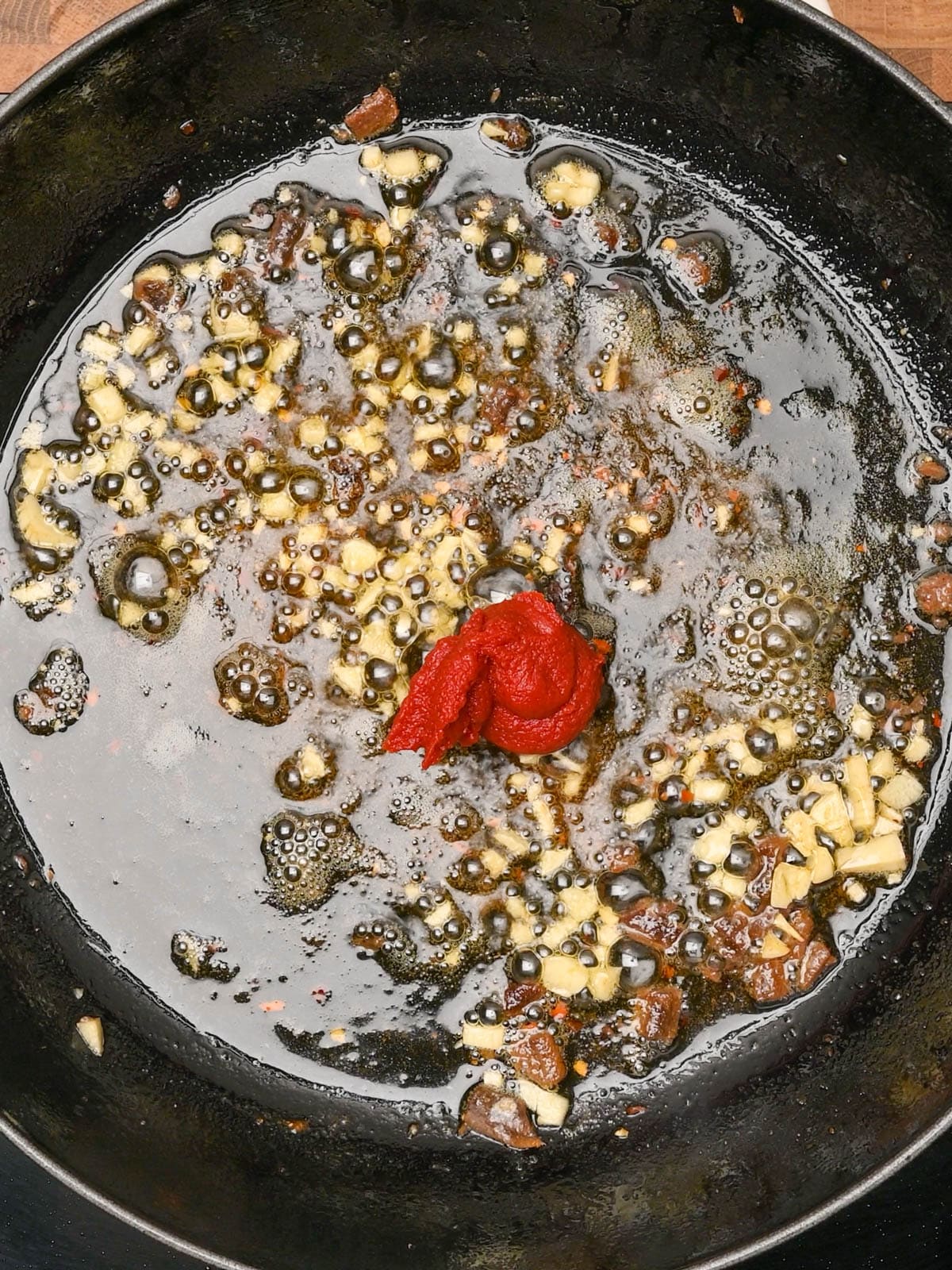 adding tomato paste to chicken puttanesca