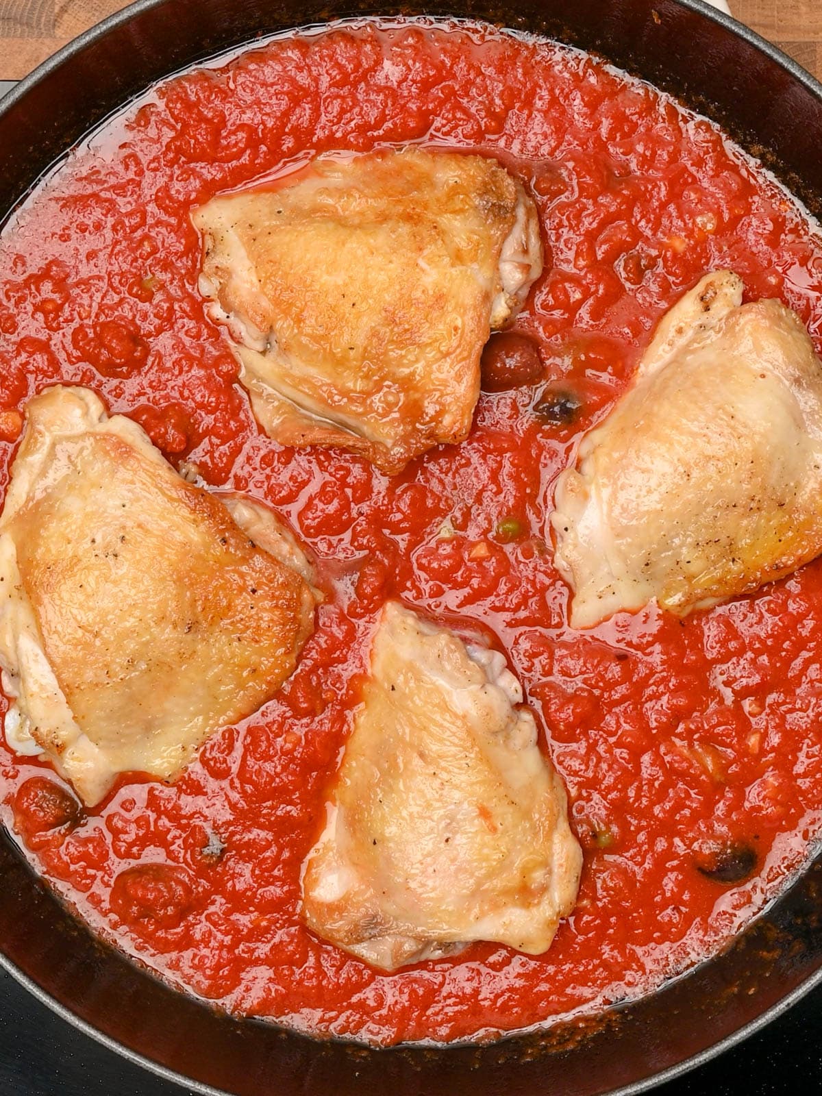 adding chicken thighs to the cooking pot
