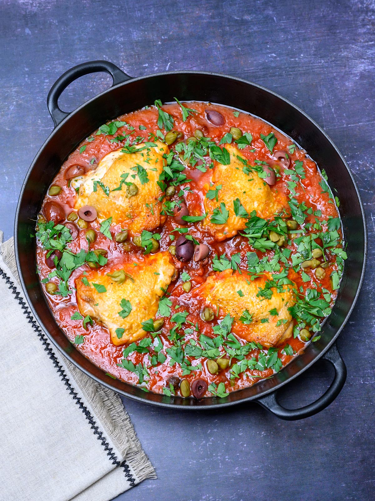 black pan with chicken thighs in a red sauce