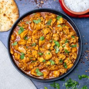 curry on a plate with rice and naan on the side