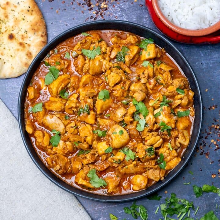curry on a plate with rice and naan on the side