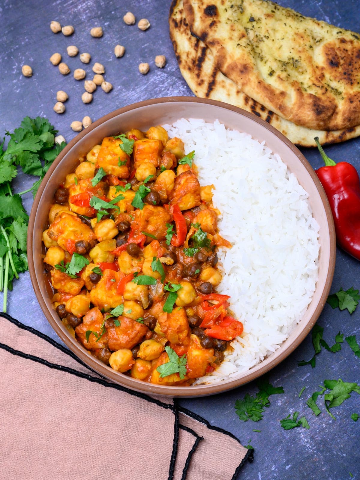 A bowl of chickpea curry with naan on the side