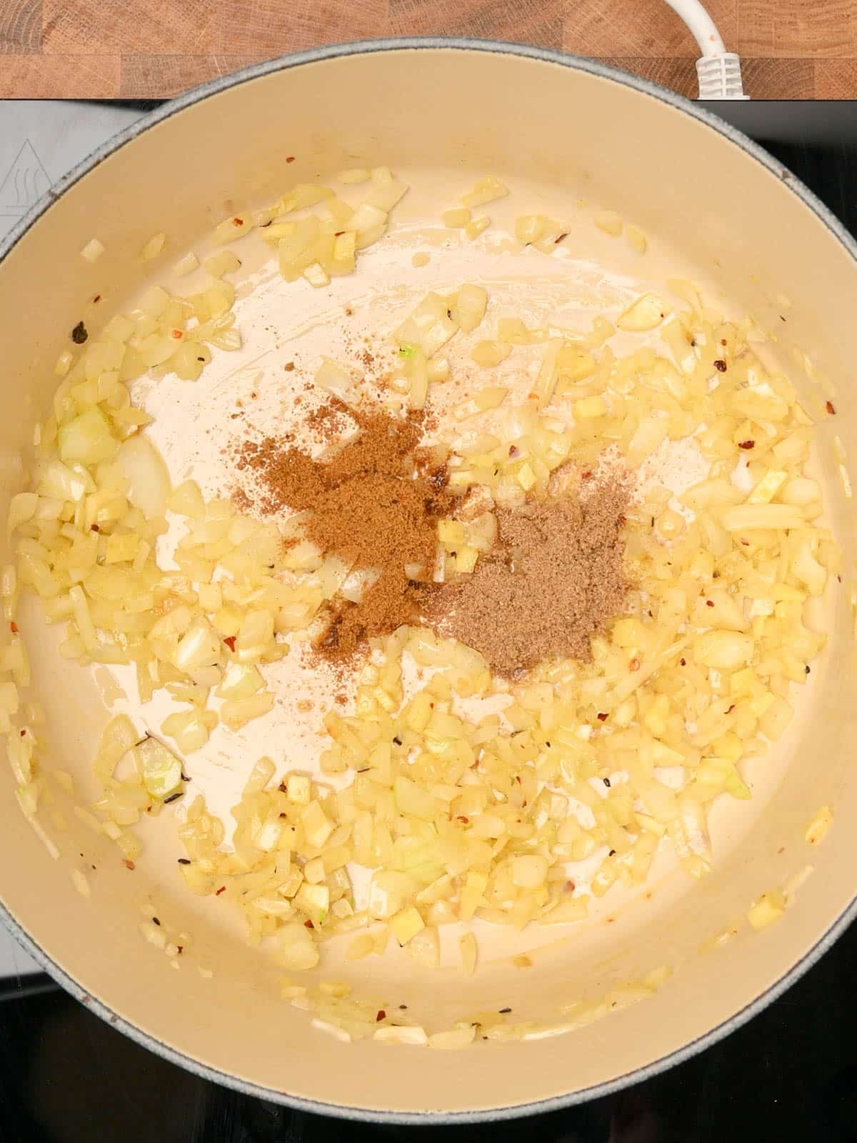 adding spices to a carrot and lentil soup