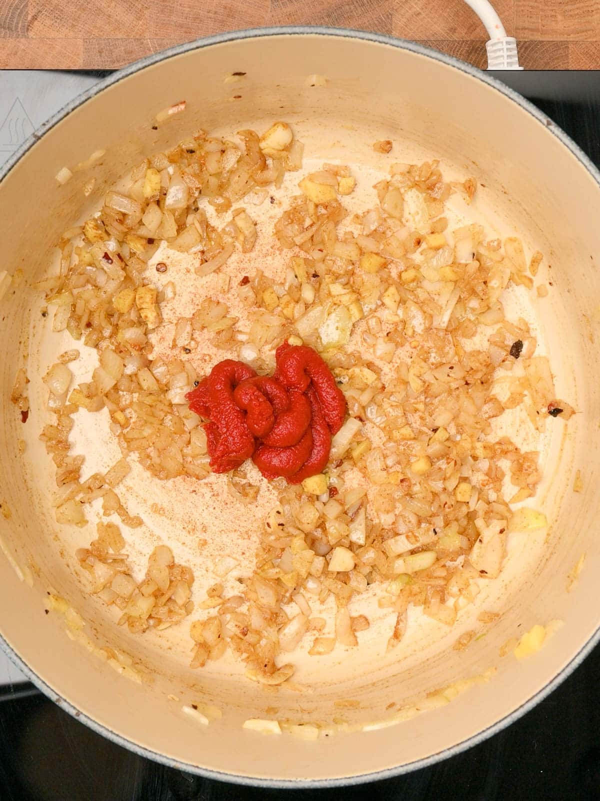 adding tomato paste to a carrot and lentil soup