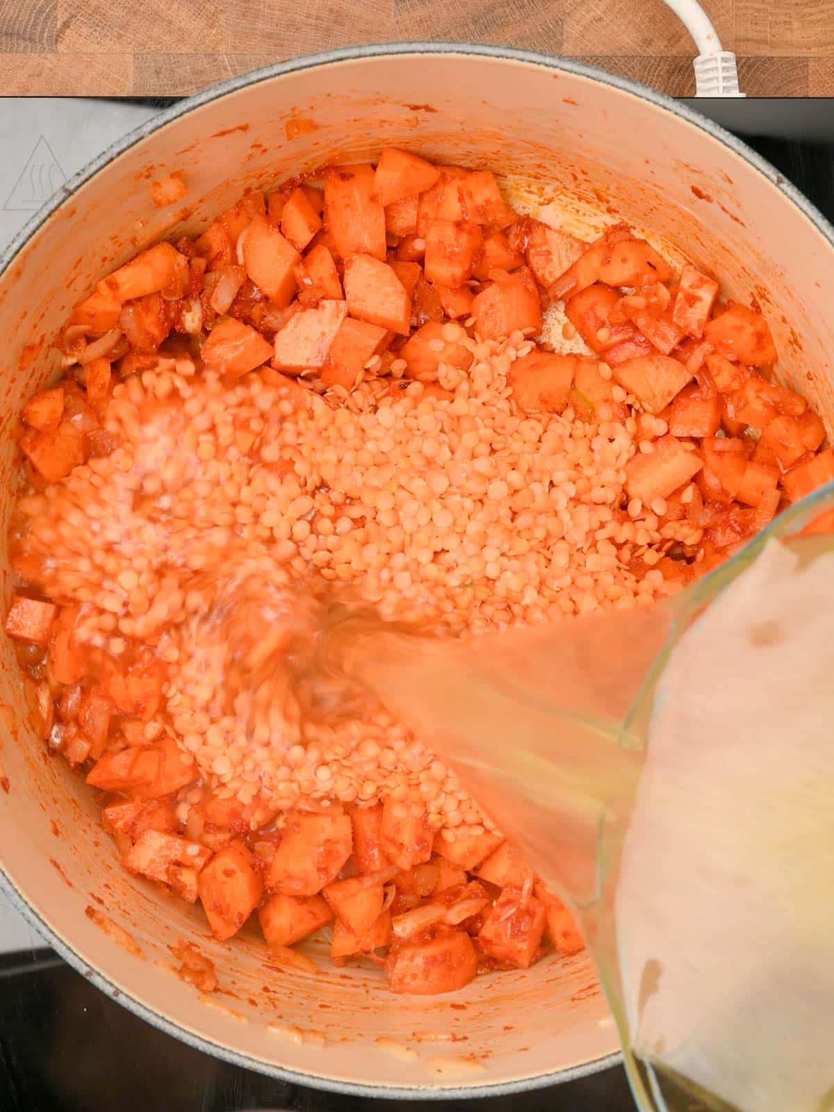 adding vegetable stock to the cooking pot