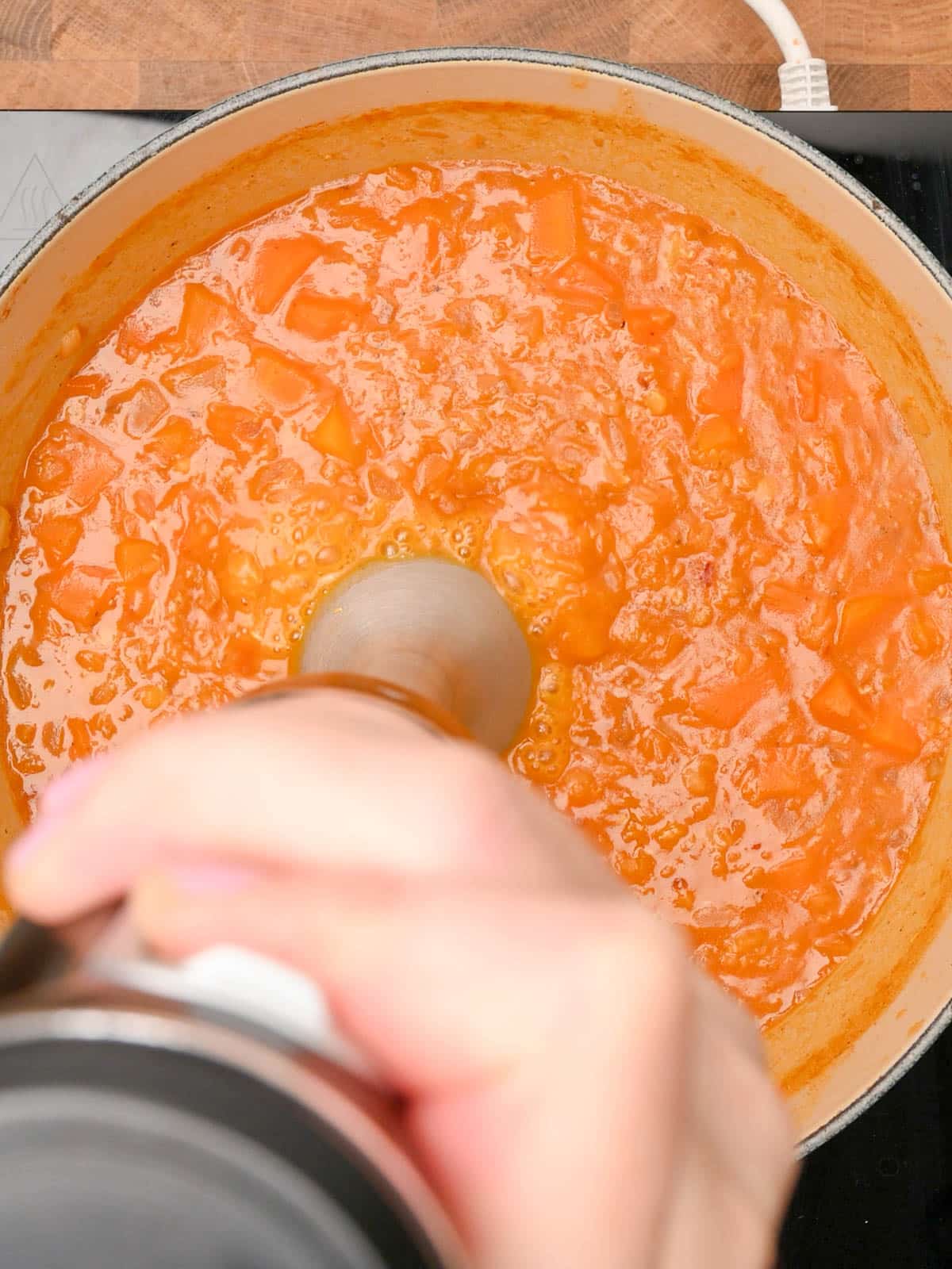 blending the soup with a hand blender