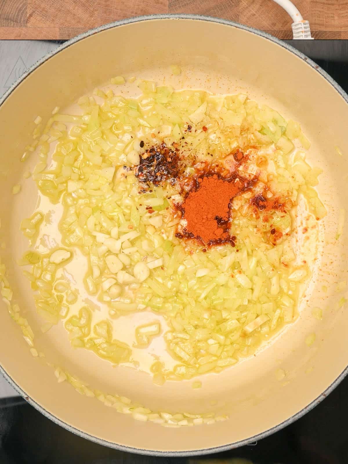 Adding spices to a roasted red pepper and tomato soup.