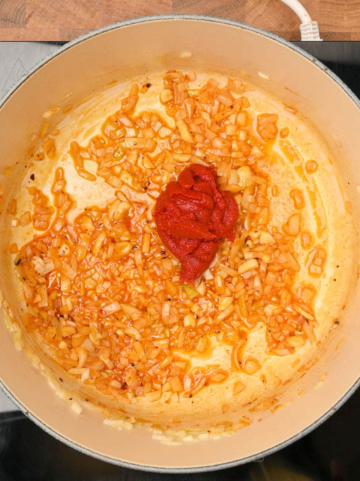 Adding tomato paste to roasted red pepper and tomato soup.