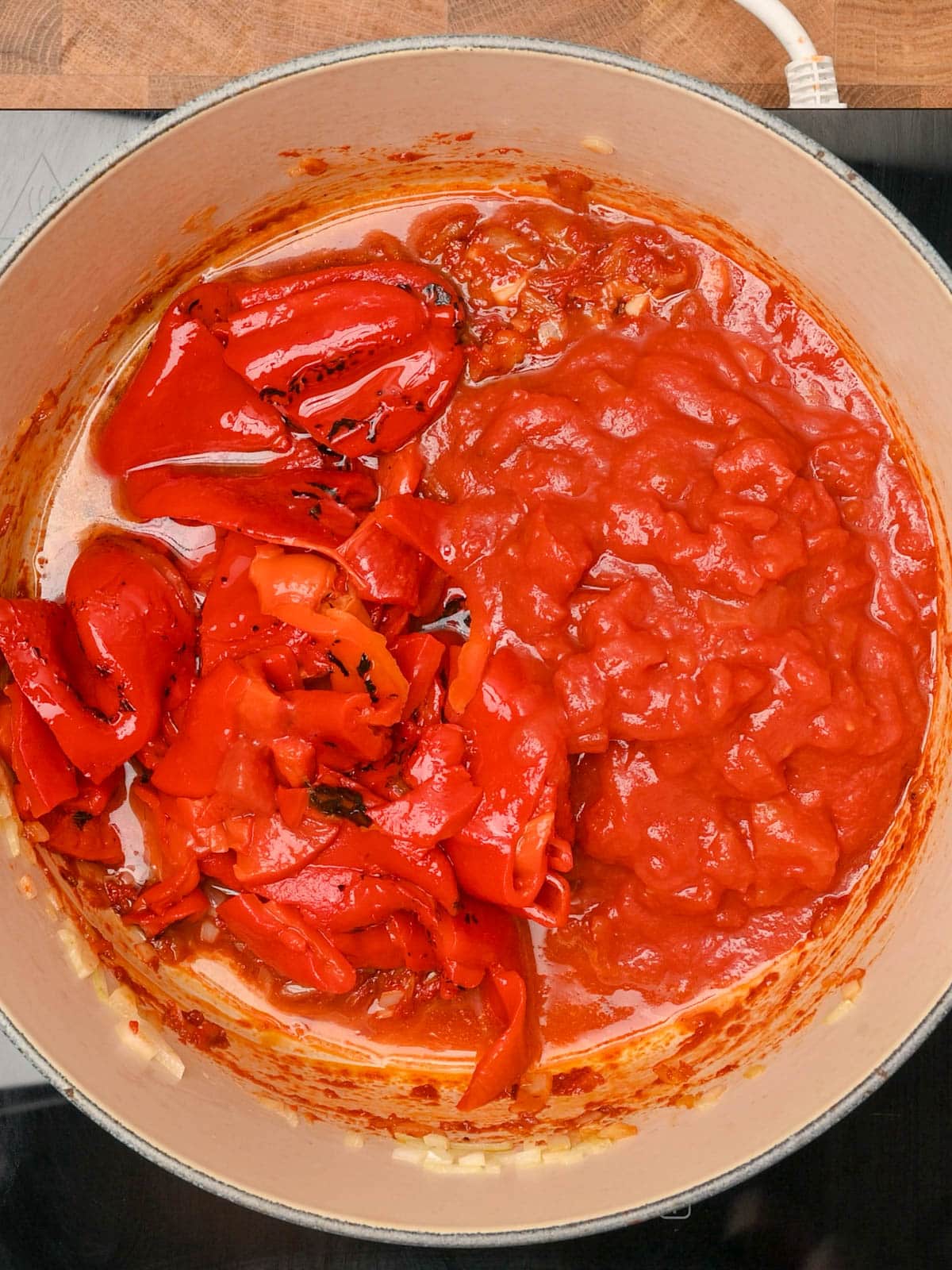 Adding diced tomatoes and peppers to the cooking pot