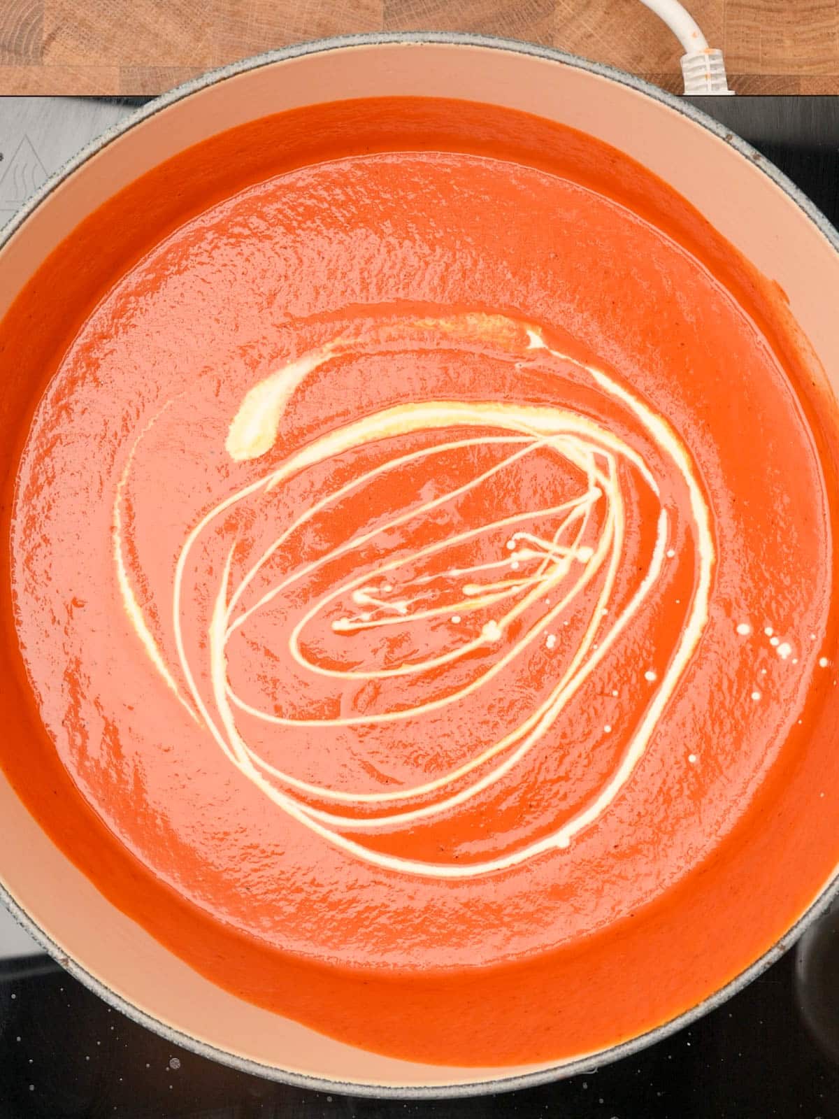 Adding heavy cream to the finished soup.