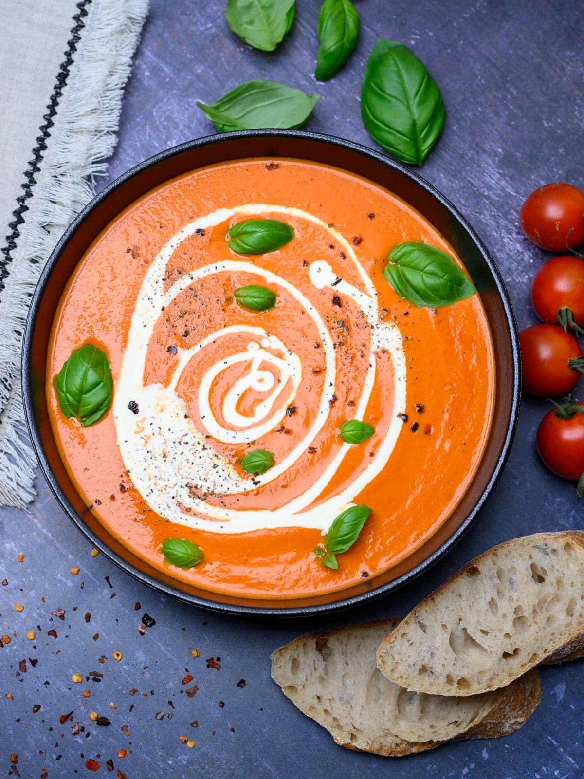 A bowl of tomato soup with sliced bread on the side.