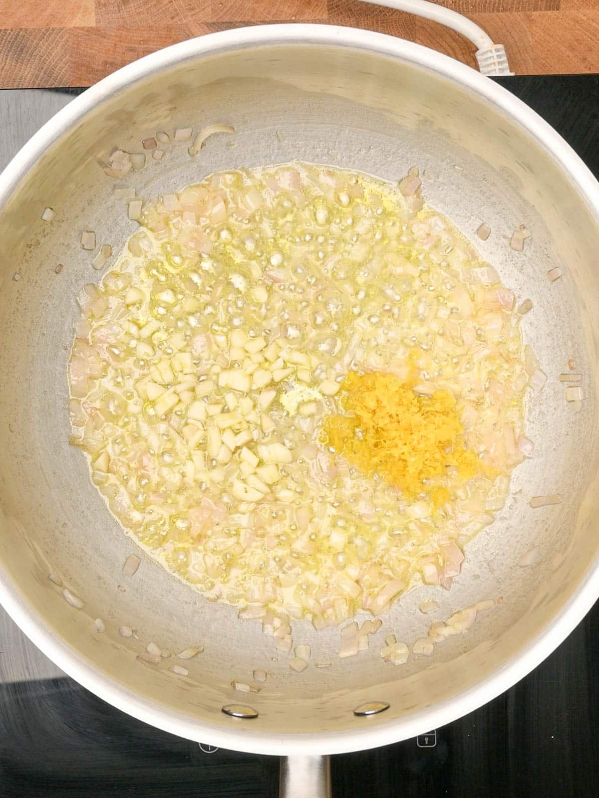 adding garlic and lemon zest to a Creamy Lemon Pasta Sauce