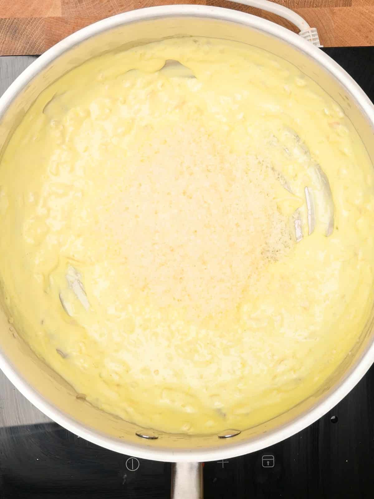 adding parmesan to the creamy sauce
