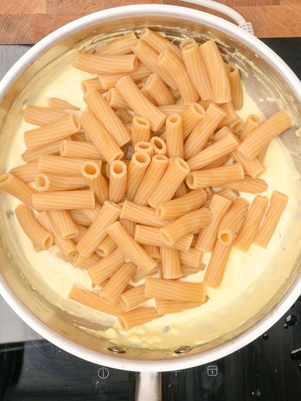 Adding cooked pasta to the creamy lemon sauce