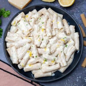 black bowl of penne with lemon zest on top
