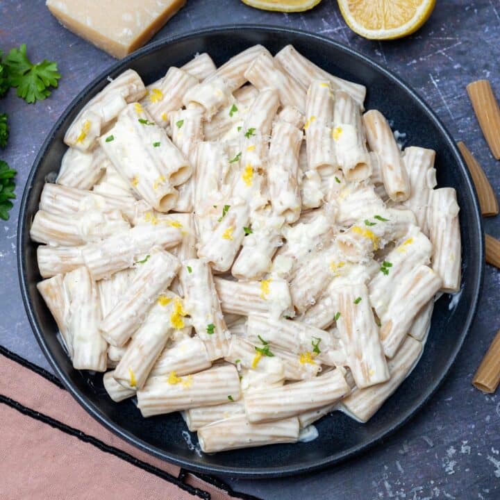 black bowl of penne with lemon zest on top