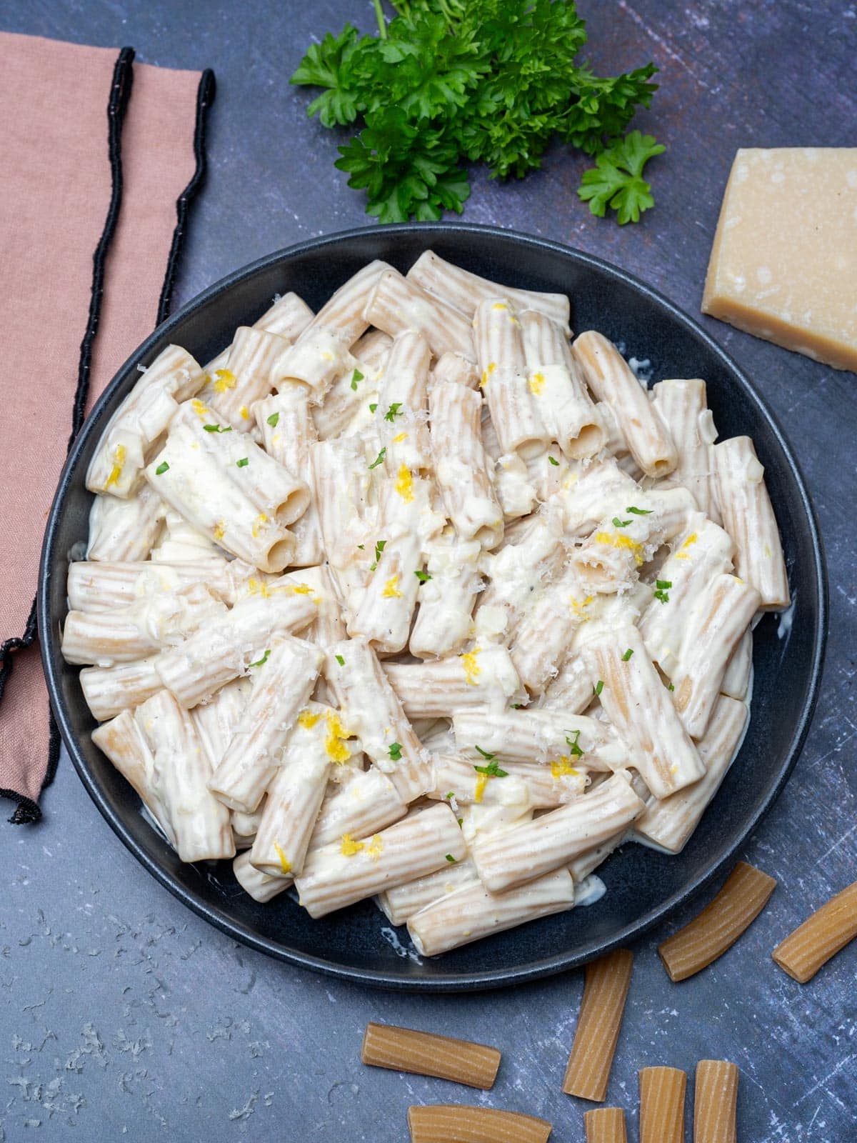 bowl of pasta with parsley and parmesan on the side