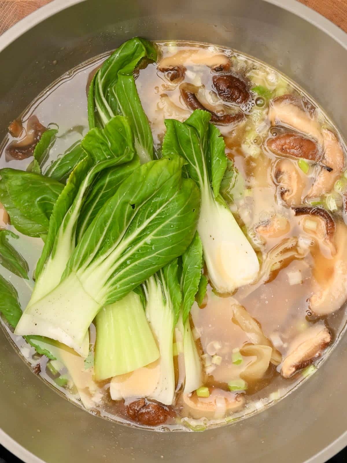adding bok choy to the cooking pot