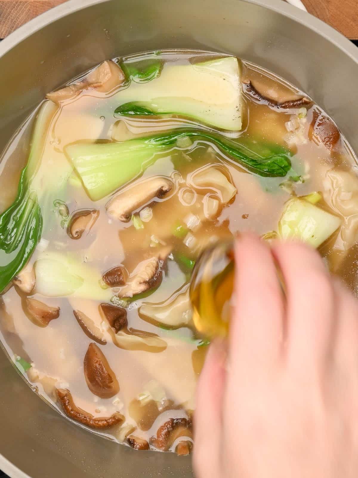 adding sesame oil to the cooking pot