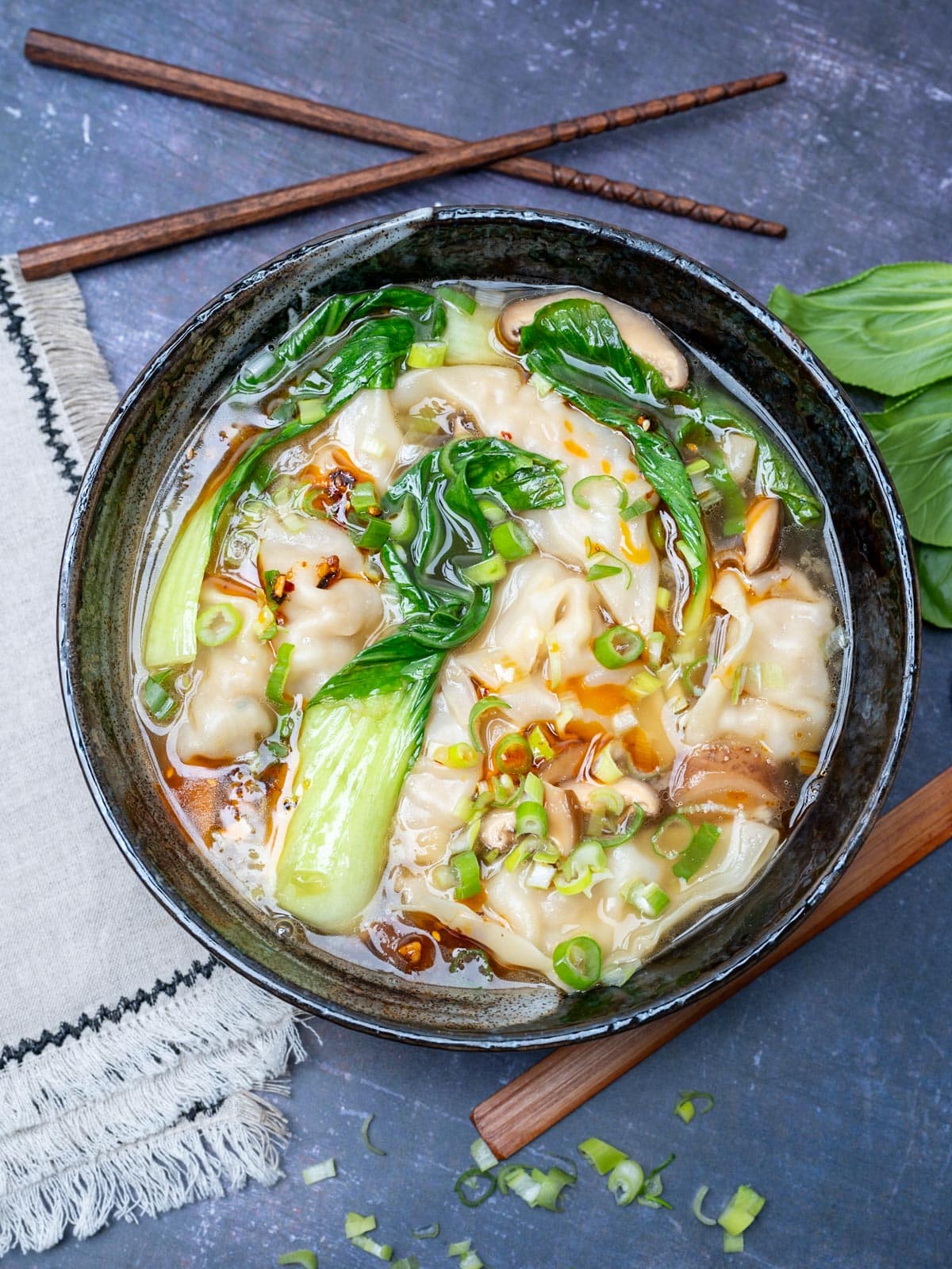 a bowl of wonton soup with spring onions
