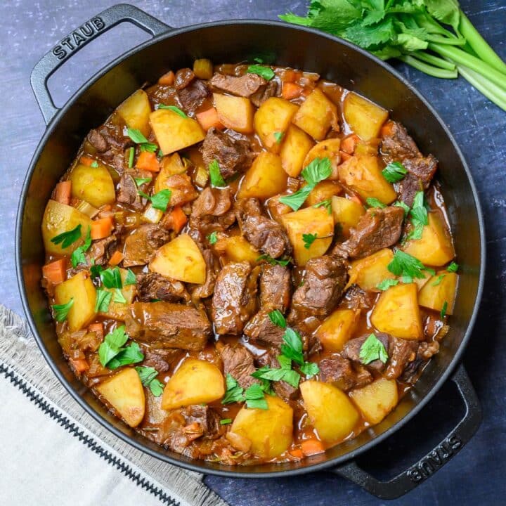 black pan with potato, carrots and pieces of meat