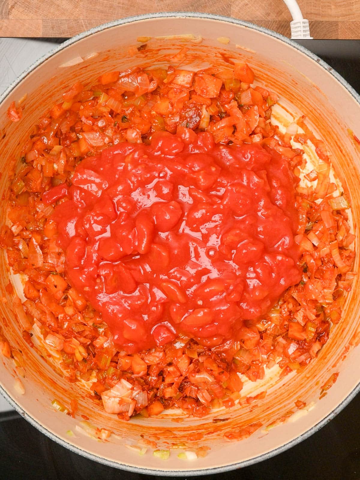 adding tomatoes to the cooking pot