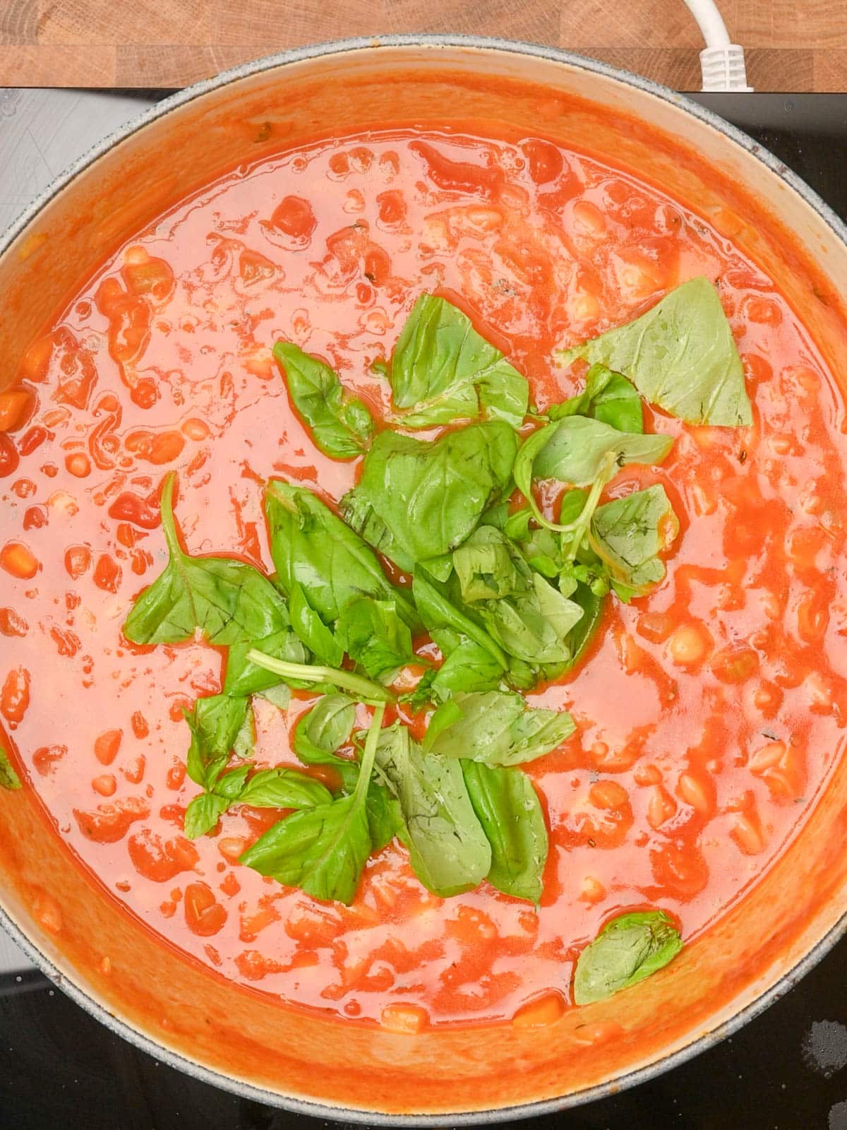 adding basil to chickpea orzo soup